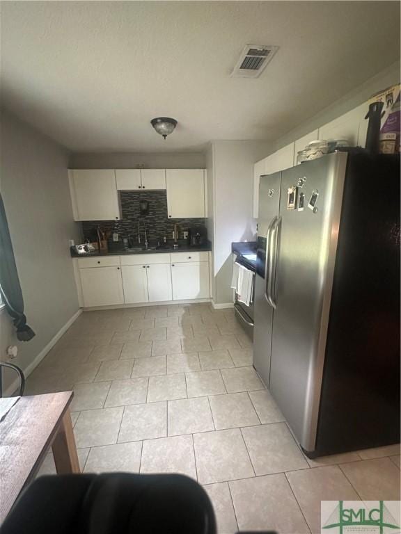 712 Fleming Rd, Hinesville, GA 31313 - kitchen featuring range, visible vents, stainless steel refrigerator with ice dispenser, dark countertops, and decorative backsplash