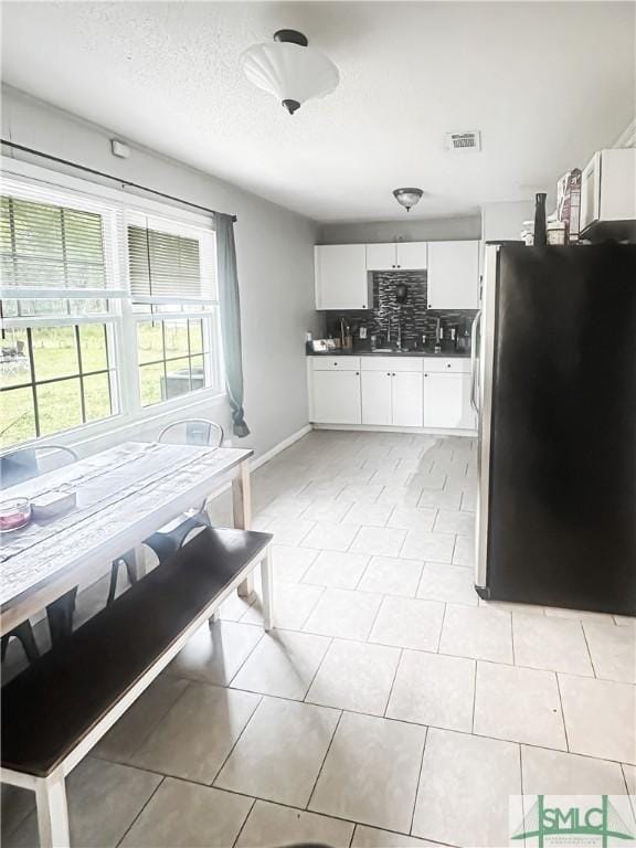712 Fleming Rd, Hinesville, GA 31313 - kitchen featuring decorative backsplash, freestanding refrigerator, white cabinetry, and visible vents