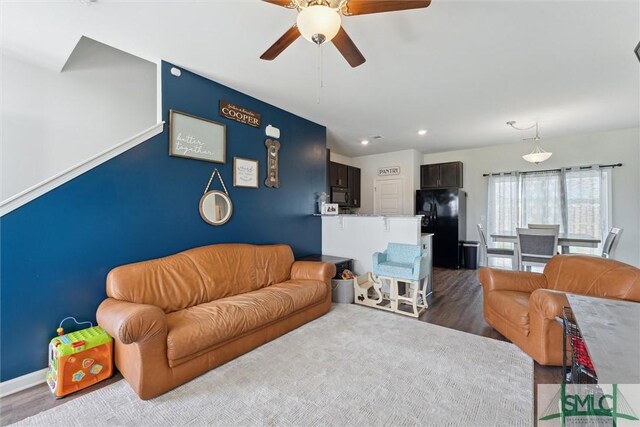 living room with an accent wall, a ceiling fan, recessed lighting, baseboards, and dark wood-style floors