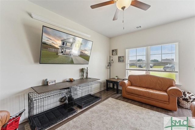 living area with wood finished floors, baseboards, a ceiling fan, and visible vents