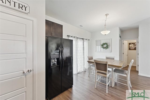 kitchen featuring dark brown cabinets, visible vents, light wood finished floors, and black fridge