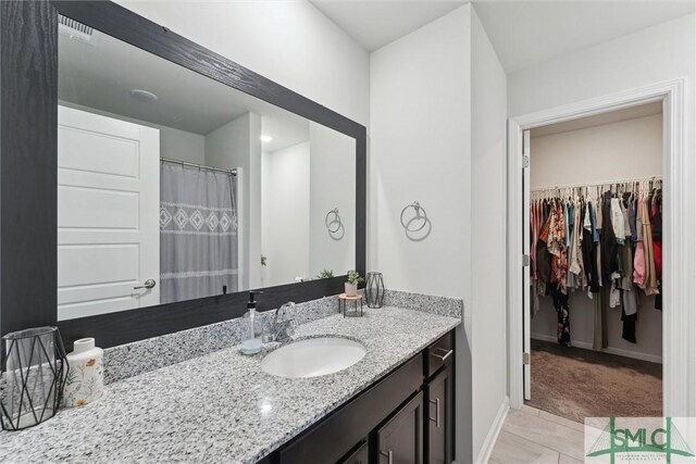 full bath featuring a spacious closet, baseboards, and vanity