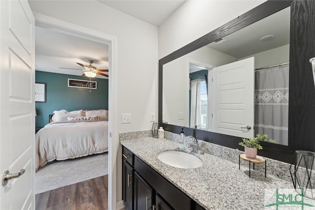 ensuite bathroom with ceiling fan, vanity, ensuite bath, visible vents, and wood finished floors