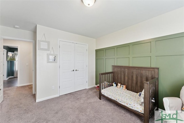 carpeted bedroom featuring a closet, baseboards, and a nursery area