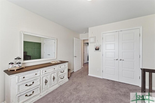 bedroom featuring a closet, baseboards, and light colored carpet