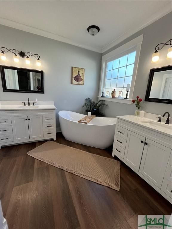full bathroom featuring a soaking tub, a sink, ornamental molding, and wood finished floors