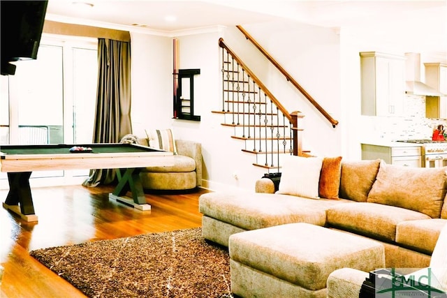 living room with pool table, wood finished floors, baseboards, ornamental molding, and stairs