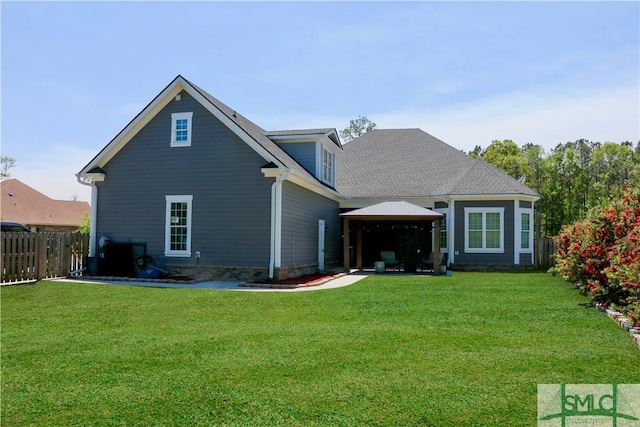 back of house featuring a lawn, a gazebo, and fence