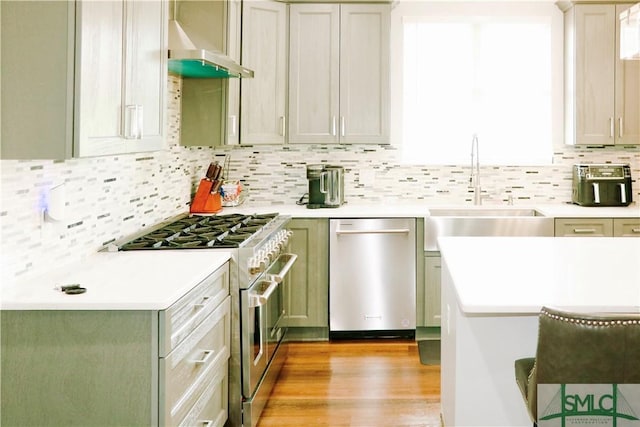 kitchen featuring a sink, appliances with stainless steel finishes, range hood, and light countertops
