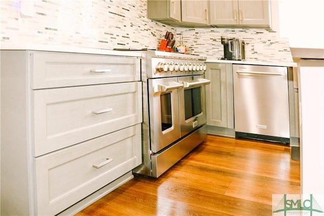 kitchen with light countertops, light wood-style flooring, appliances with stainless steel finishes, and backsplash