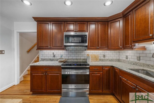 229 Golden Dr, Rincon, GA 31326 - kitchen with light stone countertops, appliances with stainless steel finishes, decorative backsplash, and a sink