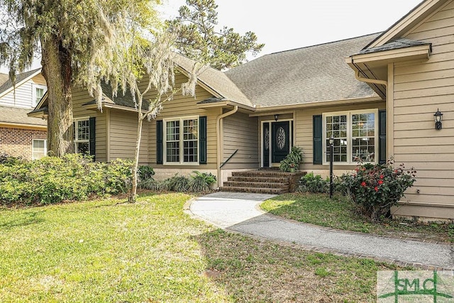 view of front of house with a shingled roof and a front lawn
