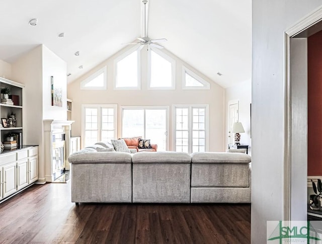 living area featuring high vaulted ceiling, ceiling fan, a high end fireplace, and dark wood-style flooring