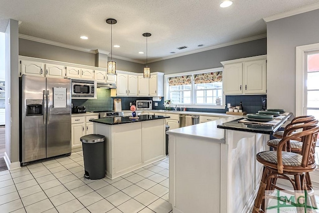 kitchen featuring a peninsula, white cabinetry, backsplash, and appliances with stainless steel finishes