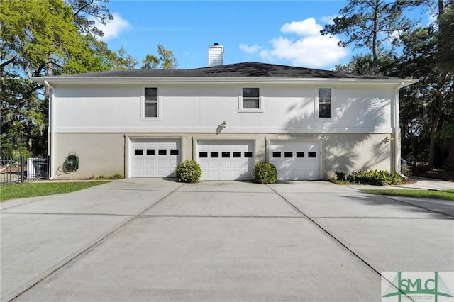 116 Brevard Ct, Savannah, GA 31410 - view of side of home featuring stucco siding, driveway, a garage, and a chimney