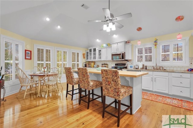 116 Brevard Ct, Savannah, GA 31410 - kitchen featuring stainless steel appliances, lofted ceiling, a kitchen breakfast bar, backsplash, and white cabinetry