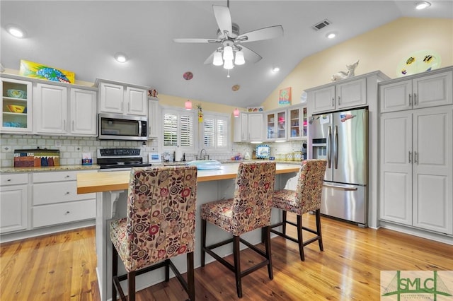 116 Brevard Ct, Savannah, GA 31410 - kitchen with stainless steel appliances, lofted ceiling, glass insert cabinets, ceiling fan, and a breakfast bar area