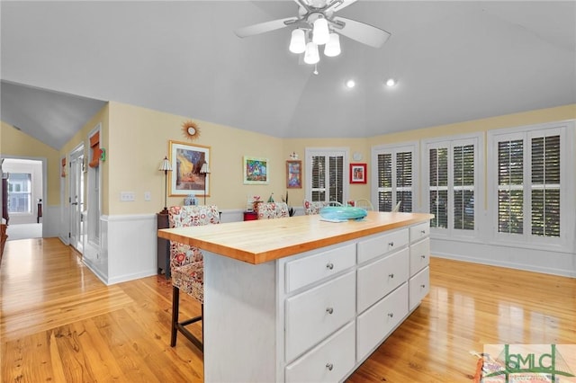 116 Brevard Ct, Savannah, GA 31410 - kitchen featuring lofted ceiling, white cabinets, light wood-style flooring, a breakfast bar area, and a wainscoted wall