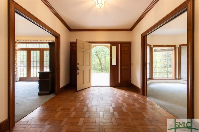 foyer entrance featuring crown molding, french doors, baseboards, and carpet flooring