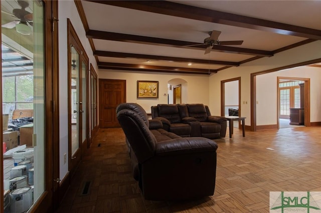 living area featuring arched walkways, plenty of natural light, baseboards, and beam ceiling