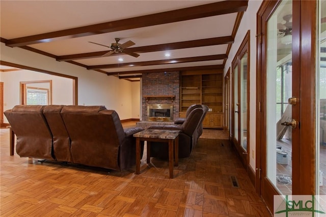 living room featuring visible vents, baseboards, a brick fireplace, ceiling fan, and beam ceiling