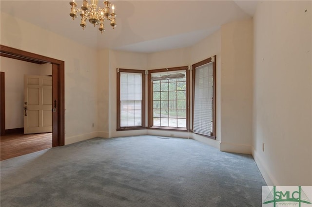 carpeted spare room featuring baseboards and a chandelier