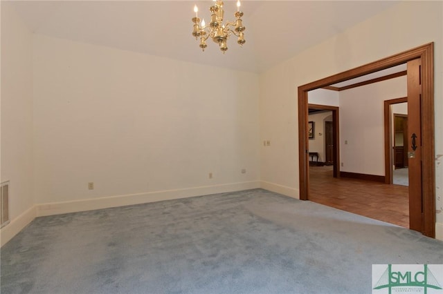 spare room with baseboards, visible vents, a notable chandelier, and carpet