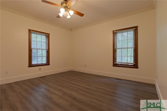 empty room with dark wood finished floors, baseboards, ornamental molding, and a healthy amount of sunlight