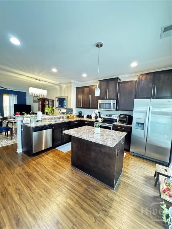 226 Ventura Pl, Pooler, GA 31322 - kitchen with appliances with stainless steel finishes, hanging light fixtures, light stone countertops, dark brown cabinets, and recessed lighting