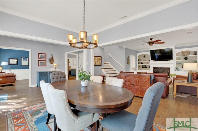 5 Wigmore Cir, Savannah, GA 31410 - dining area with crown molding, a fireplace, wood finished floors, and ceiling fan with notable chandelier