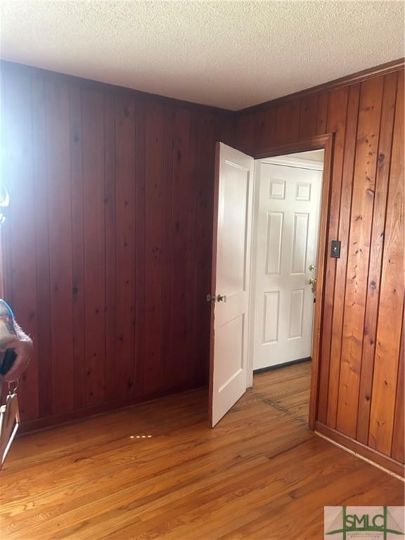 30 Lawton Ave, Savannah, GA 31404 - spare room with light wood-style floors, wood walls, and a textured ceiling