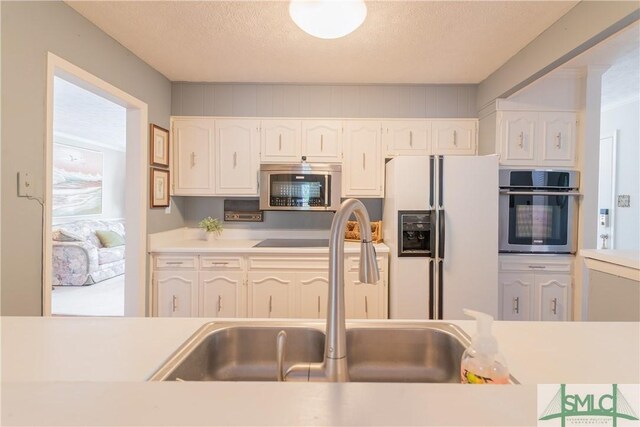 3411 Ponderosa Rd, Portal, GA 30450 - kitchen featuring a textured ceiling, white cabinetry, a sink, light countertops, and stainless steel appliances