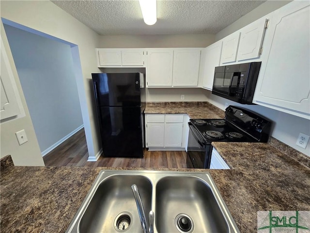 kitchen with dark countertops, dark wood-type flooring, a textured ceiling, a sink, and black appliances