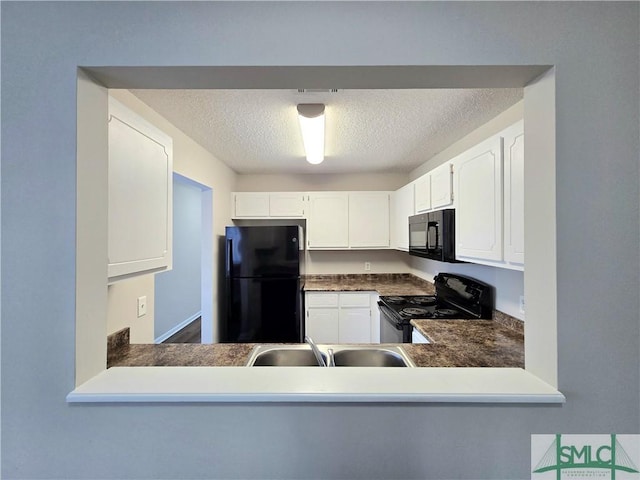 kitchen with a sink, white cabinets, black appliances, and a textured ceiling