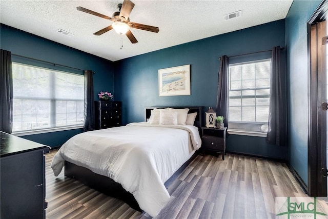 bedroom with visible vents, multiple windows, and wood finished floors