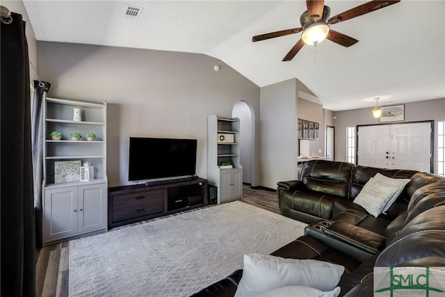 living room with lofted ceiling, visible vents, ceiling fan, arched walkways, and wood finished floors