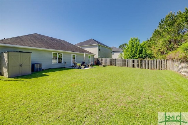 view of yard featuring an outbuilding, a fenced backyard, cooling unit, and a storage unit