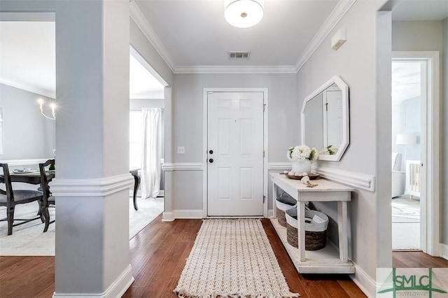 foyer entrance with dark wood-style flooring, baseboards, ornamental molding, and visible vents