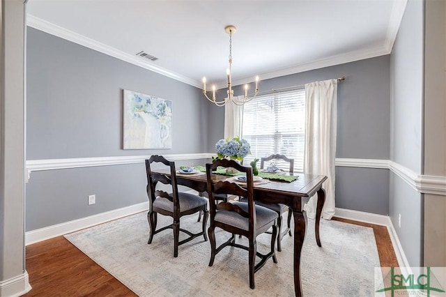 dining room featuring crown molding, visible vents, a chandelier, wood finished floors, and baseboards