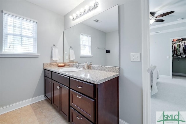 bathroom with visible vents, baseboards, a ceiling fan, a walk in closet, and vanity