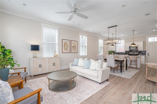 living area with ornamental molding, visible vents, recessed lighting, and light wood-style floors