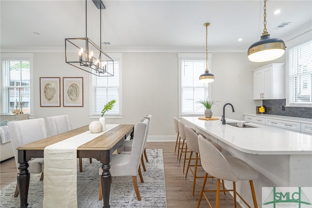 dining area featuring visible vents, baseboards, an inviting chandelier, light wood-type flooring, and crown molding