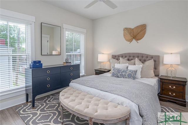 bedroom featuring ceiling fan, multiple windows, baseboards, and wood finished floors