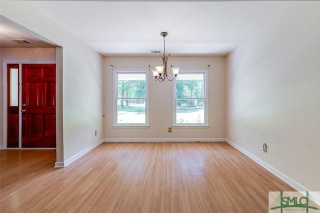 unfurnished dining area featuring baseboards, light wood finished floors, a notable chandelier, and visible vents