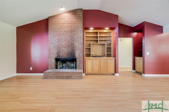 unfurnished living room with baseboards, light wood-type flooring, a brick fireplace, and lofted ceiling