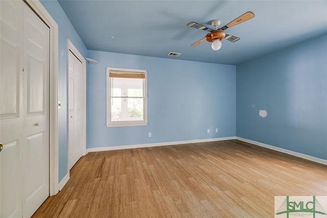 unfurnished bedroom with wood finished floors, baseboards, a ceiling fan, and visible vents