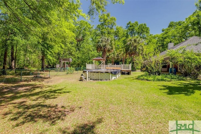 view of yard with fence, a playground, and a covered pool
