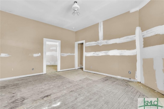 spare room featuring baseboards and wood finished floors