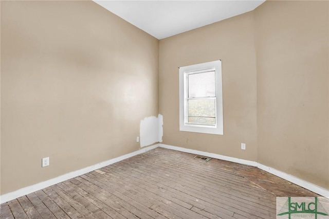 spare room featuring baseboards, wood-type flooring, and visible vents