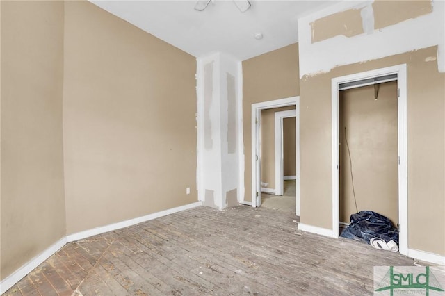unfurnished bedroom with a closet, hardwood / wood-style flooring, and baseboards